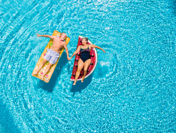 Two people relaxing on inflatable mattresses in a pool